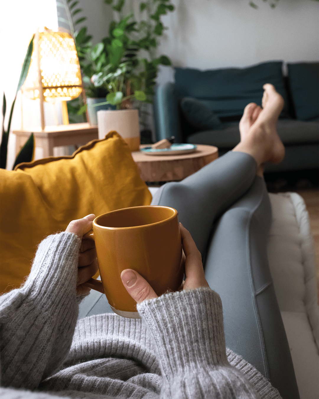 Person relaxing on a sofa with a hot drink