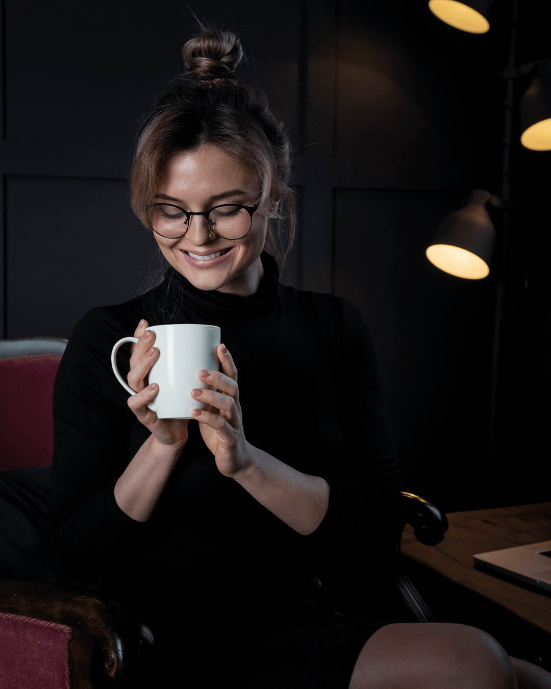 Peron holding and looking into a hot drink and smiling